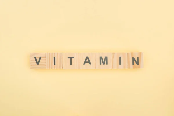Top View Vitamin Lettering Made Wooden Cubes Yellow Background — Stock Photo, Image