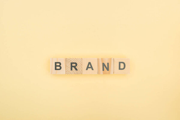 top view of brand lettering made of wooden cubes on yellow background