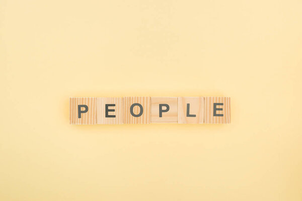 top view of people lettering made of wooden cubes on yellow background