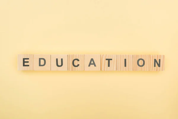 Draufsicht Auf Bildungsschriftzug Aus Holzwürfeln Auf Gelbem Hintergrund — Stockfoto