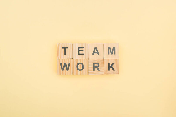 top view of team work lettering made of wooden blocks on yellow background