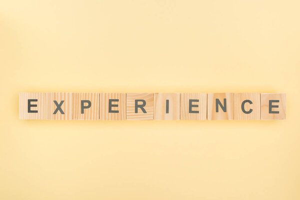 top view of experience lettering made of wooden cubes on yellow background