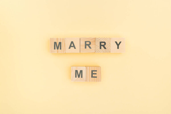 top view of marry me lettering made of wooden blocks on yellow background