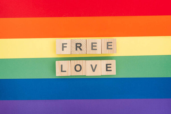 верхний вид свободной любви буквы из деревянных блоков на бумажном радужном фоне

