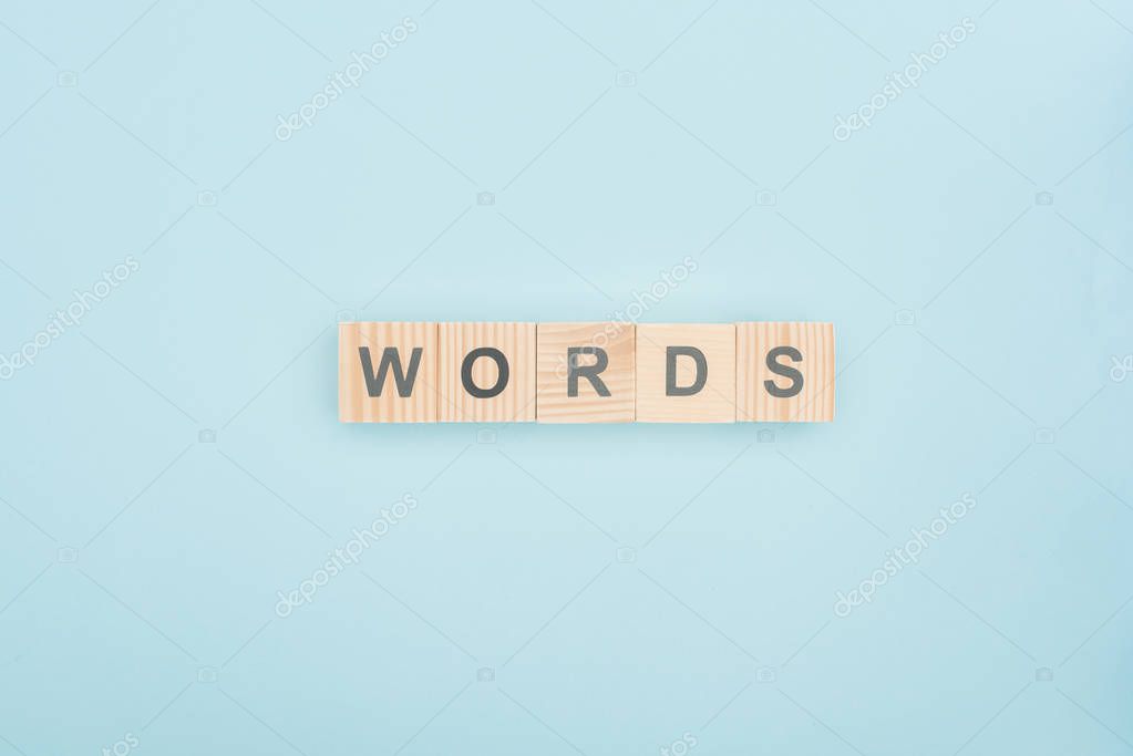 Top view of words lettering made of wooden cubes on blue background