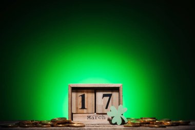 cube calendar with date near golden coins and shamrock on green background clipart