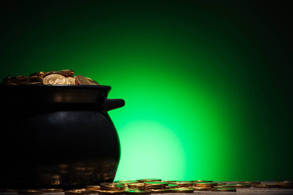 pot with golden coins on st patricks day on green background