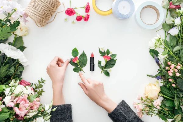 白い背景の上の花に囲まれた口紅に近いバラ Boutonnieres を触れる女性の手のトリミング ビュー — ストック写真