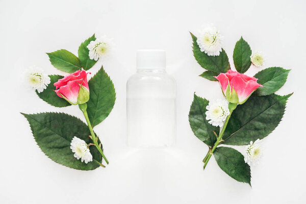 top view of clear empty bottle between boutonnieres isolated on white