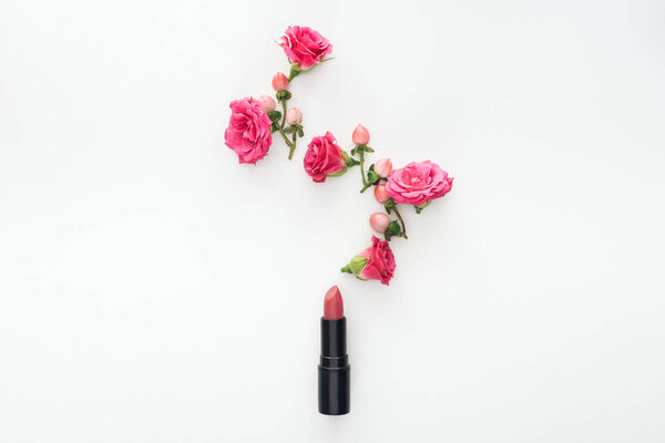 top view of composition with roses buds, berries and lipstick on white background