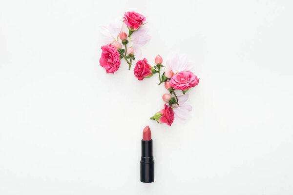 top view of composition with roses buds, berries, petals and pink lipstick on white background