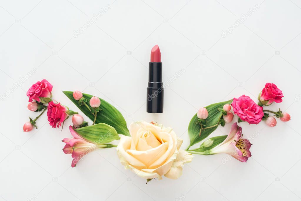 top view of composition with alstroemeria, roses, berries and lipstick on white background