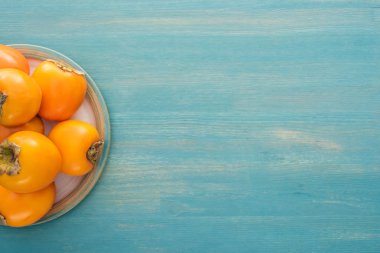 Olgun ve bütün persimmons üstten görünüm kopya alanı ile cam tabakta