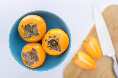 selective focus of persimmons on blue glass plate and slices on cutting board  clipart