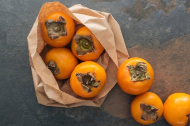 top view of ripe and whole persimmons in paper packet  clipart