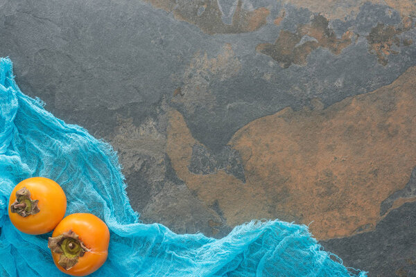 top view of orange persimmons on blue cloth with copy space