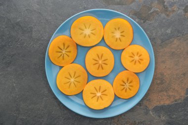 üstten görünüm Orange hurma mavi plaka üzerine dilimlenmiş. 