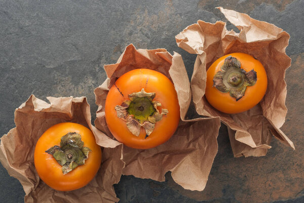 top view of whole ripe orange persimmons in paper 