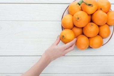 mandalina ile plaka yakınındaki el kısmi görünümünü kopya alanı ahşap beyaz zemin üzerine