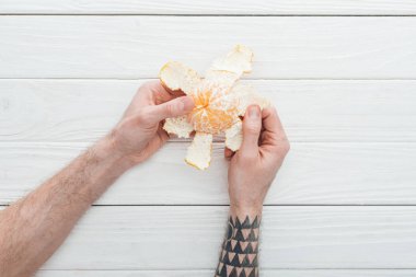 Dövmeli adamın mandalina Beyaz ahşap arka plan üzerinde peeling kısmi görünümü
