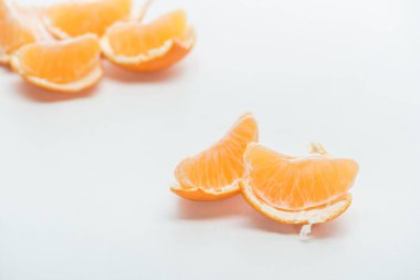 selective focus of tangerine slices with peel on white background clipart