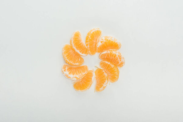 flat lay with peeled tangerine slices arranged in circle on white background