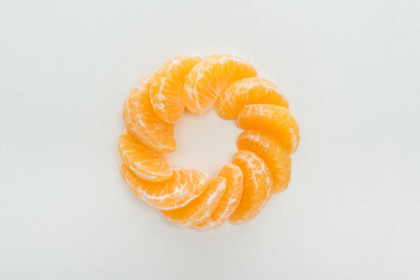 flat lay with peeled tangerine slices arranged in circle on white background