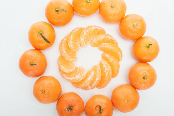 flat lay with circles of peeled tangerine slices and whole tangerines on white background