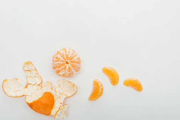 top view of whole tangerine, slices and peel on white background 