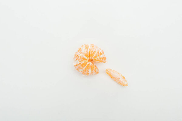 top view of whole peeled tangerine and slice on white background