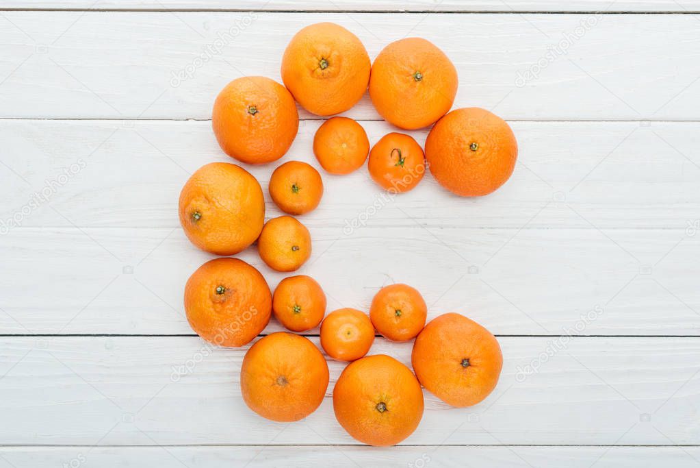 top view of letter C made of fresh tangerines on wooden white surface