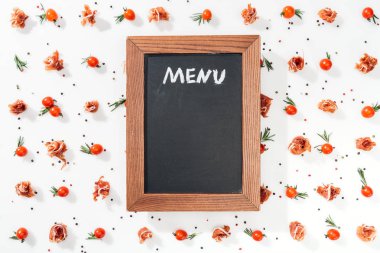  chalk board with menu lettering among tomatoes, prosciutto, spices and leaves  clipart
