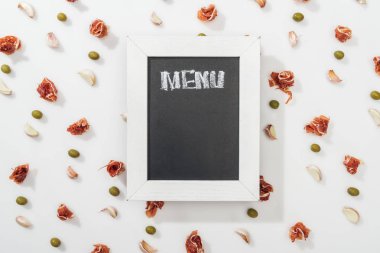 top view of chalk board with menu lettering among prosciutto, olives and garlic cloves clipart