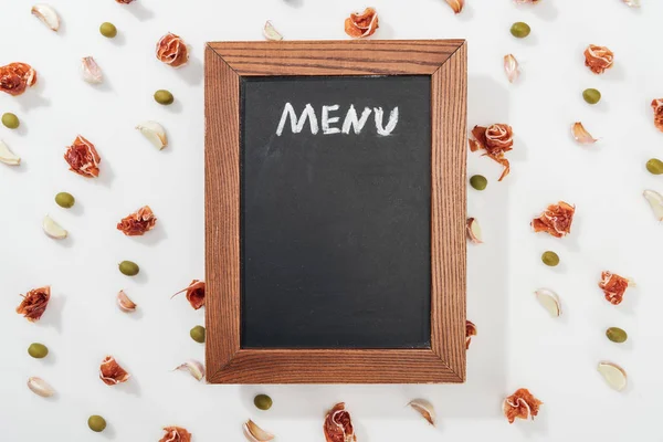 Top view of chalk board with menu lettering among prosciutto, olives and garlic cloves — Stock Image Top View Chalk Board Menu Lettering Prosciutto Olives Garlic Cloves Royalty Free Stock Images