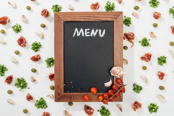 Top view of chalk board with menu lettering among prosciutto, olives, garlic cloves, greenery and cherry tomatoes — Stock Image Top View Chalk Board Menu Lettering Prosciutto Olives Garlic Cloves Royalty Free Stock Photos
