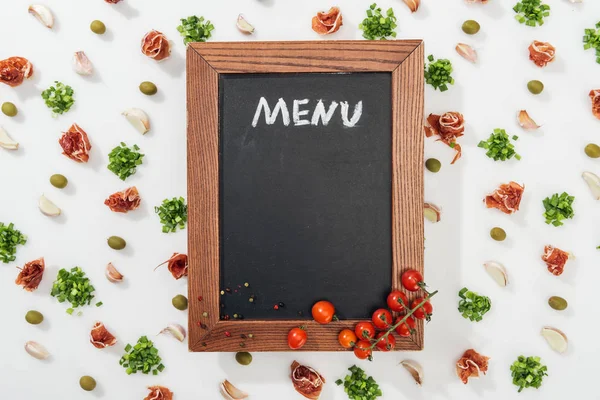 Chalk board with menu lettering among prosciutto, olives, garlic cloves, greenery and cherry tomatoes — Stock Image Chalk Board Menu Lettering Prosciutto Olives Garlic Cloves Greenery Cherry Stock Picture
