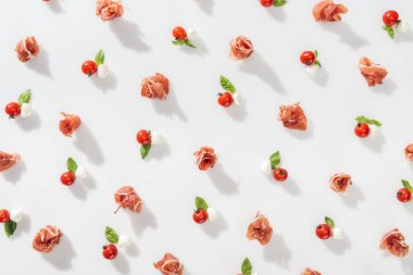 beyaz zemin üzerine kırmızı kiraz domates, mozzarella peyniri ve fesleğen lezzetli prosciutto üstten görünüm bırakır