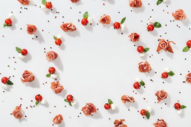 Beyaz arka plan üzerinde düz, prosciutto kırmızı kiraz domates yakınındaki yatıyordu, mozzarella peynir ve yeşil fesleğen yaprağı