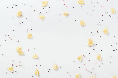 limon dilimleri üzerinde beyaz izole kırmızı ve siyah peppercorns yakınındaki düz lay 