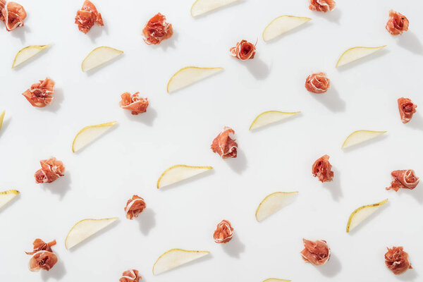 flat lay of prosciutto near sliced juicy pears on white background