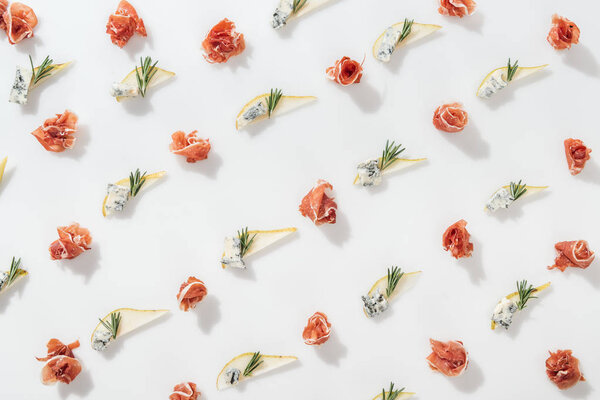 flat lay of prosciutto near sliced pears with blue cheese and rosemary twigs on white background