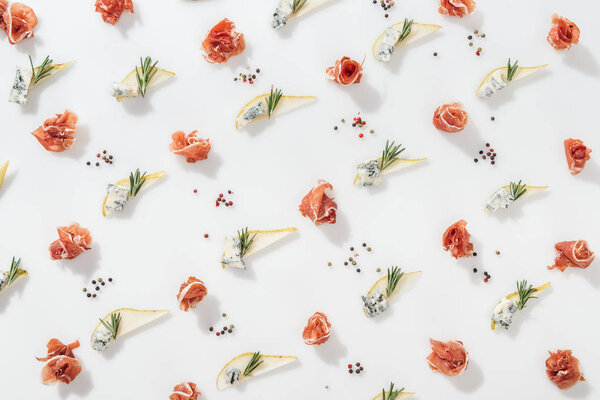 flat lay of delicious prosciutto near sliced pears with blue cheese and rosemary twigs on white background