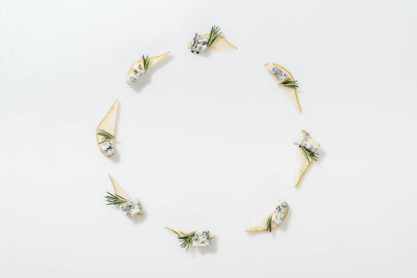 top view of sliced pears with blue cheese and rosemary twigs on white background