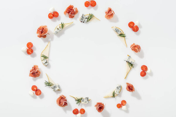 top view of sliced pears with blue cheese and rosemary twigs near tasty prosciutto, cherry tomatoes and mozzarella cheese on white background