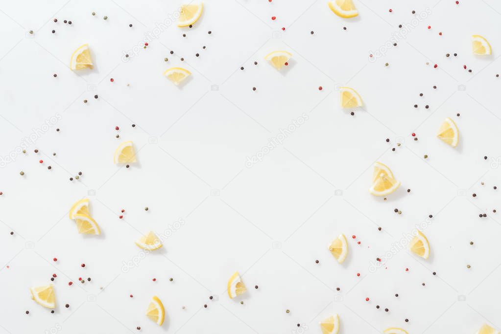 flat lay of lemon slices near red and black peppercorns isolated on white 