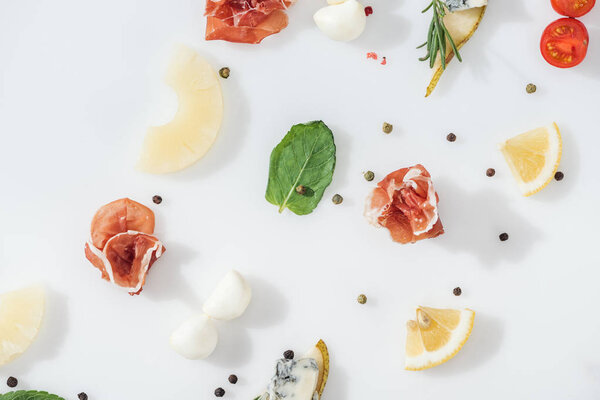 flat lay of delicious prosciutto near fresh ingredients and spices on white background