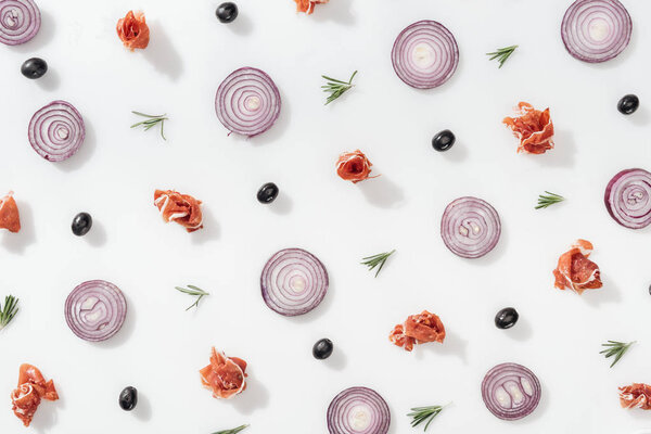 flat lay of red onion rings near prosciutto, cherry tomatoes, rosemary twigs and black olives on white background