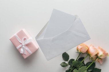 gri arka plan üzerinde pembe güller, sarılmış hediyeler, zarf ve kart Üstten Görünüm  