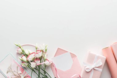 Üstten Görünüm pembe eustoma, rulo kağıt, hediyeler, zarf ve kartpostal gri arka plan üzerine sarılmış  