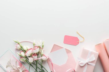 Üstten Görünüm pembe eustoma, rulo kağıt, hediyeler, zarf, etiket ve tebrik kartı gri arka plan üzerine sarılmış 